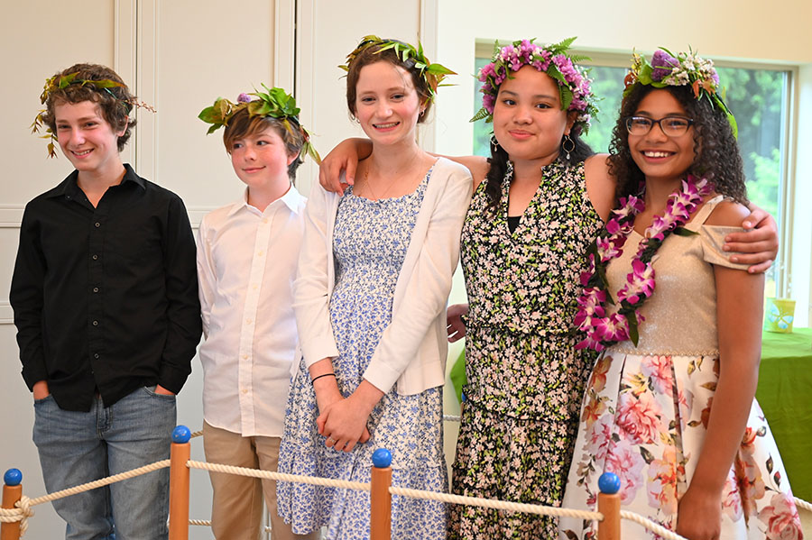 Five 6th grade graduates stand together wearing leaf crowns