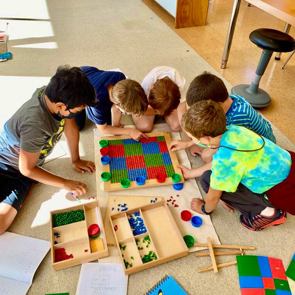 Elementary students huddled around a science project on the floor