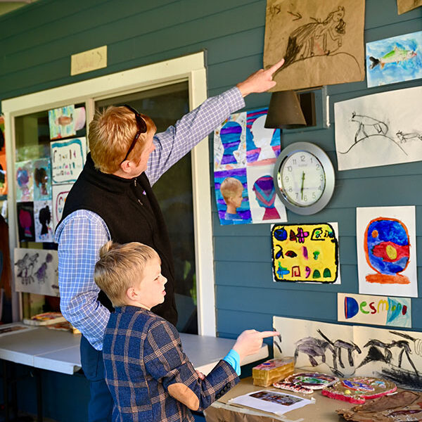 Parent and child admire the student's artwork on the wall